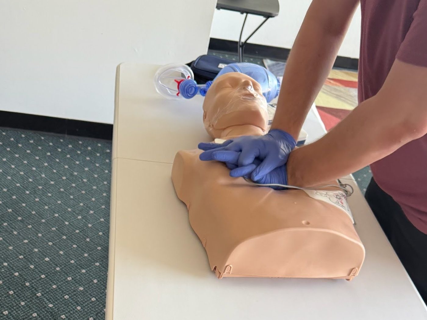 Student practicing CPR chest compressions on a training manikin during a Caribarbfrey CPR class